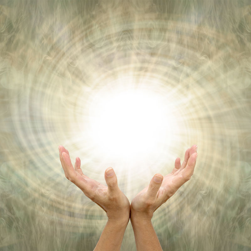 A woman's hands holding a ball of golden light with swirls.